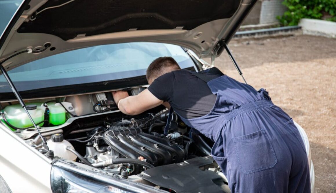 Professional mechanic at Homerton Car Repairs in Hackney E9 inspecting a vehicle underside for winter corrosion with a torch, workshop environment visible.